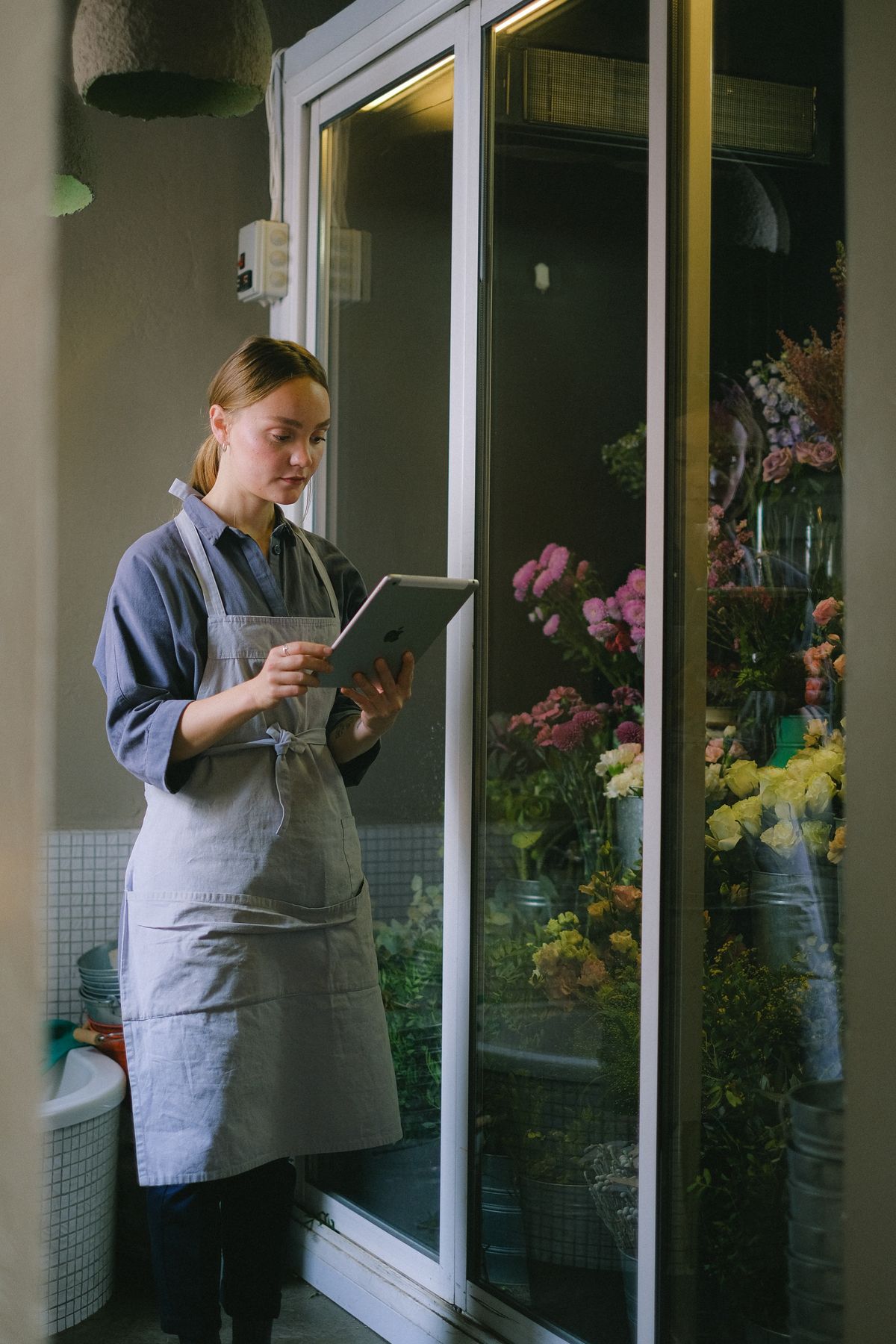 Una florista atiende pedidos desde una tableta en su tienda.